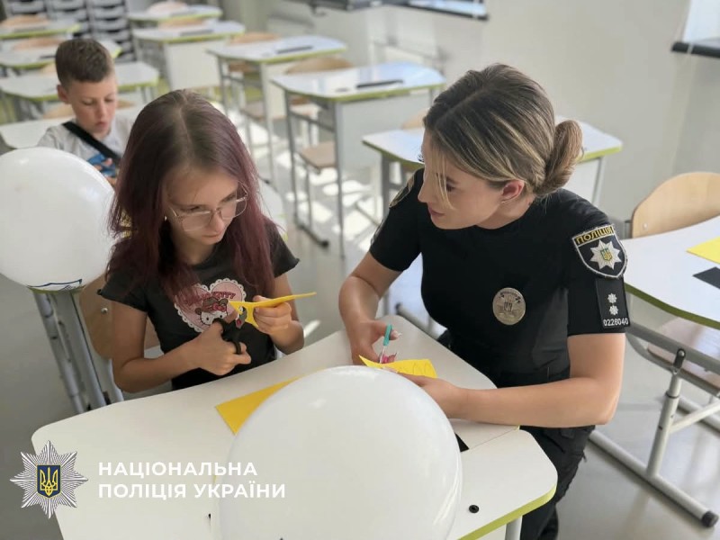 На фото поліцейська та дитина, які виготовляють сонях.