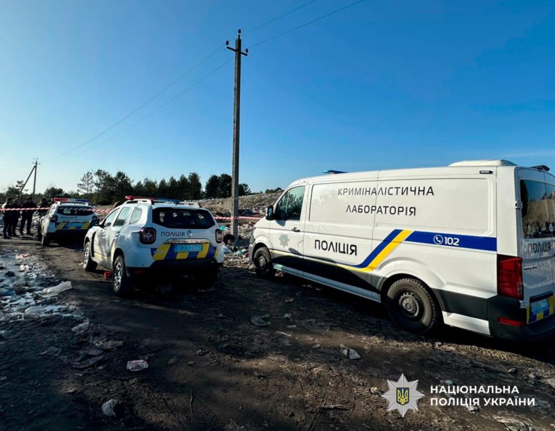 Поліцейські на місці вбивства. Біля сміттєзвалища стоять службові авто поліції та криміналістична лабораторія.