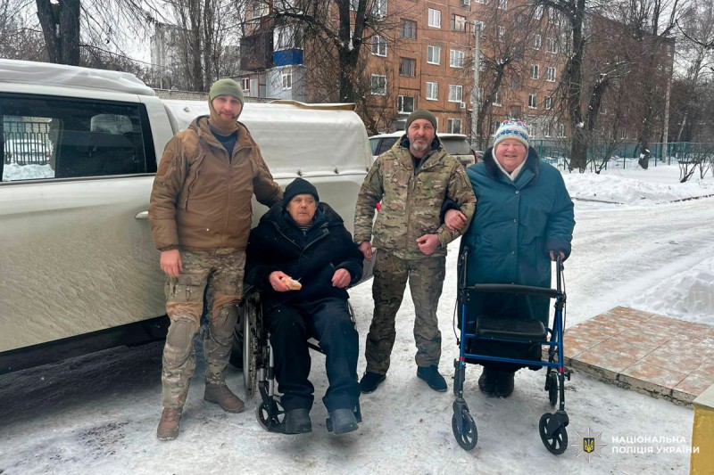Військові та цивільні допомагають людям похилого віку на засніженій вулиці.