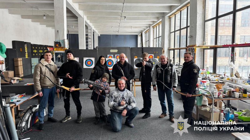 На фотографії зображено правоохоронців, які спільно з ветеранами відвідали столичний тир, де випробували свої сили у стрільбі з лука.