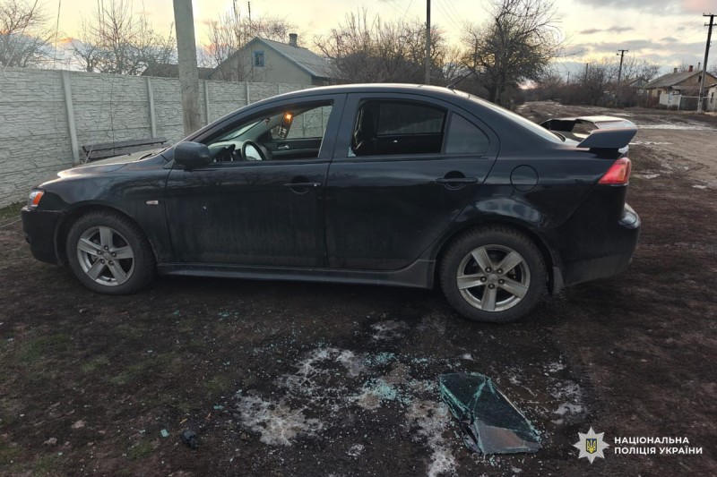 Автомобіль із пошкодженим боковим склом стоїть на ґрунтовій ділянці.