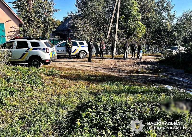 На вулиці стоять поліцейські та місцеві жителі.