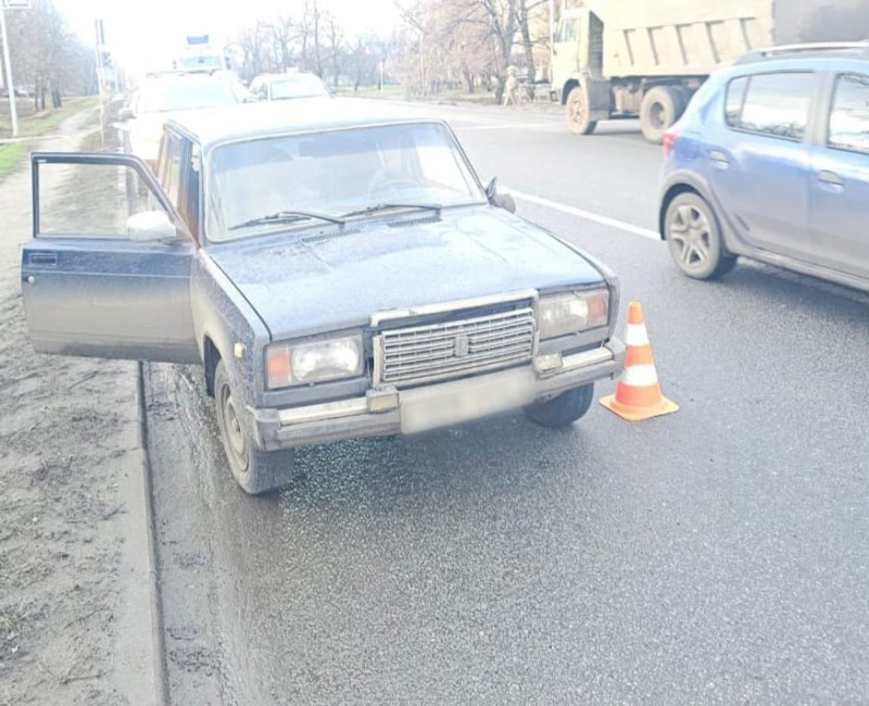 Автомобіль стоїть на узбіччі в умовах вологої дороги, двері водія відчинені, поруч рухаються інші транспортні засоби.