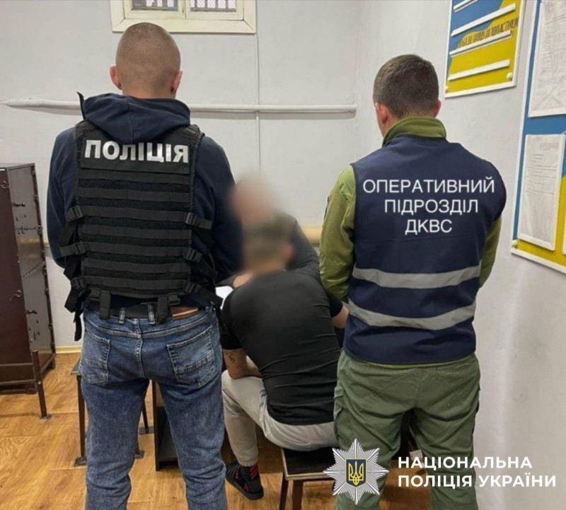 На фото зображені поліціейський та працівник оперативного підрозділу ДКВС, які стоять спиною. Перед ними порушник сидить за столом також спиною.