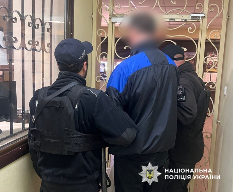 Alt text: <Двоє поліцейських тримають чоловіка>