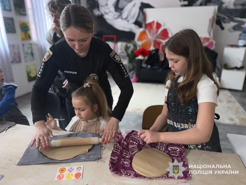 Поліцейська допомагає діткам робити виріб із глини