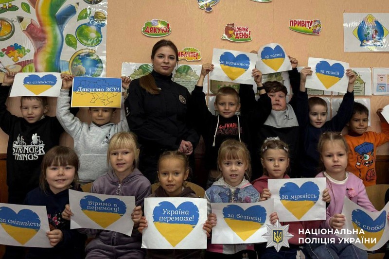 Спільне фото  поліцейської та школярів, які тримають у руках листівки зі словами подяки для ЗСУ