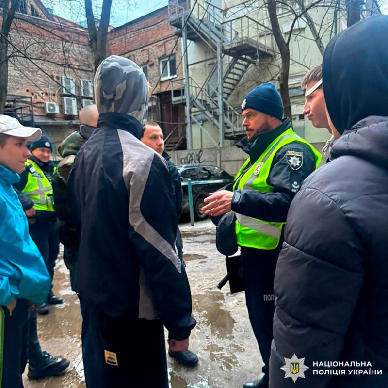 Поліцейські у формі та світловідбивних жилетах проводять інструктаж для громадян.