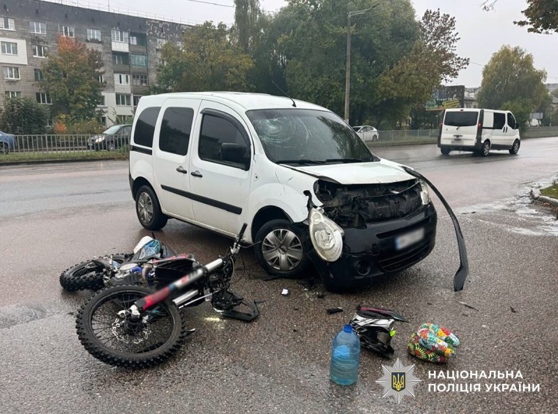 Пошкоджений автомобіль білого кольору та пошкоджений мотоцикл, що лежить на асфальтному покритті