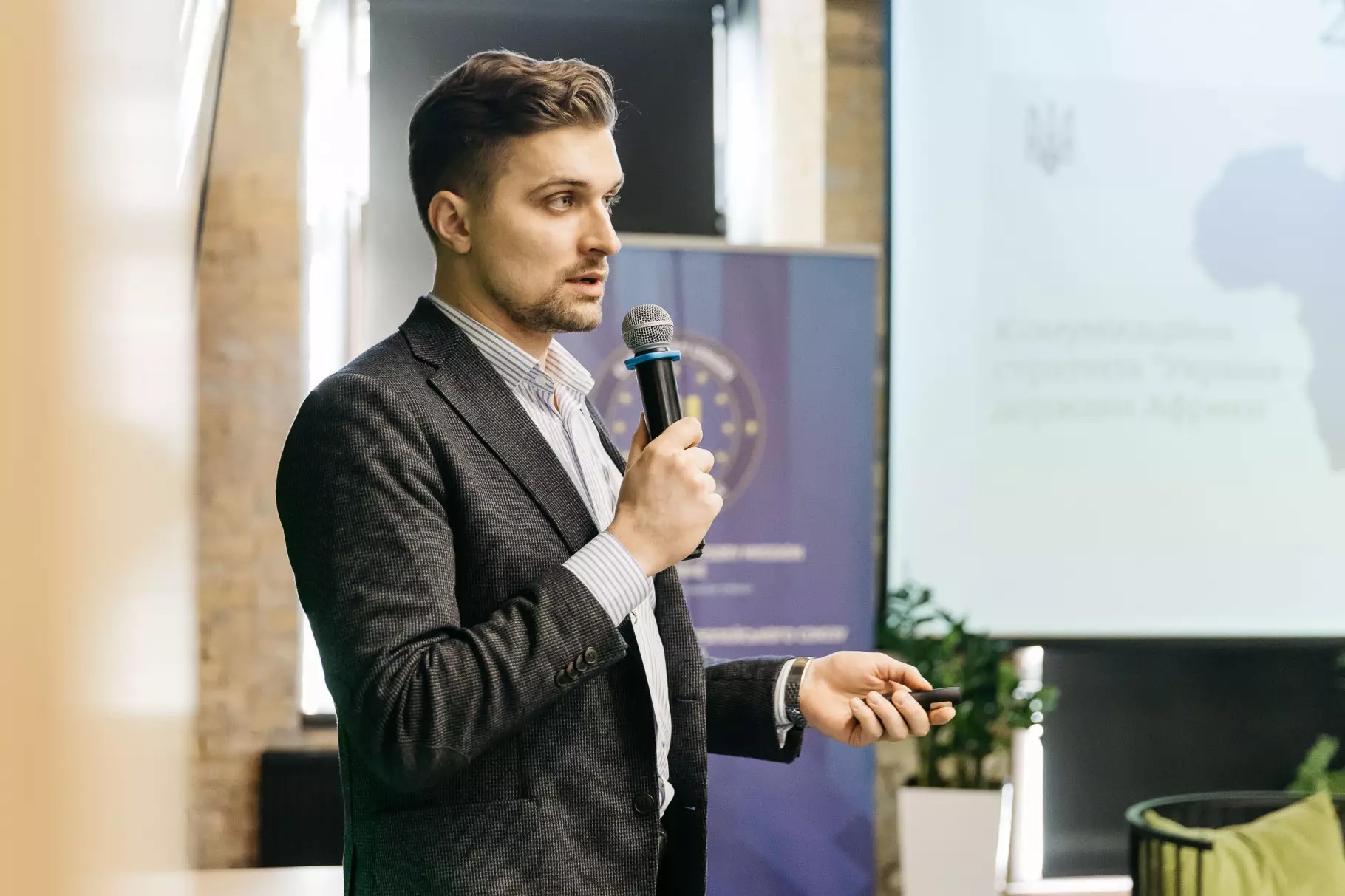Спікер Ілля Панфілов з мікрофоном в руках презентує доповідь