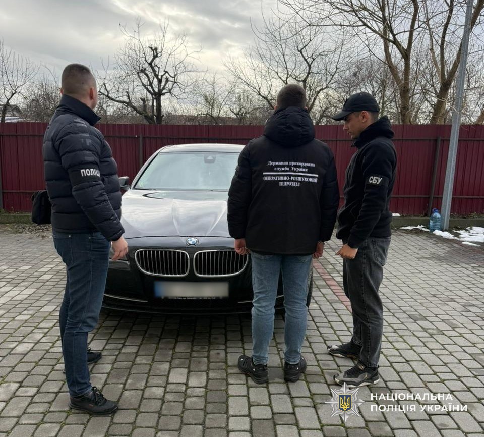 Правоохоронці біля автомобіля, який вилучили у четвертого підозрюваного учасника схеми