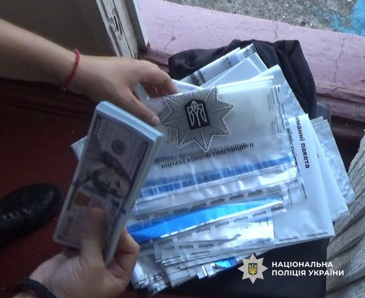 Гроші та сейф-пакет з написом "Національна Поліція України"