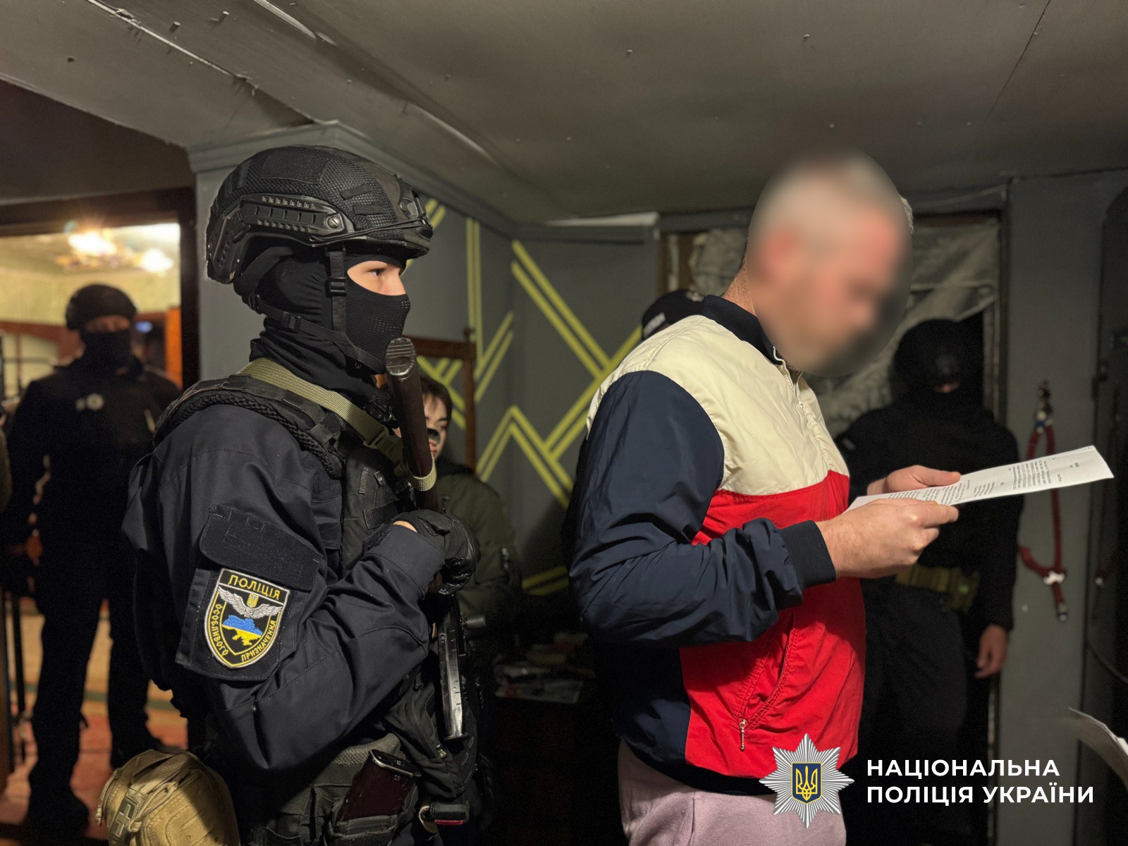 Поліцейський полку поліції особливого призначення стоїть поряд з чоловіком, який читає документи