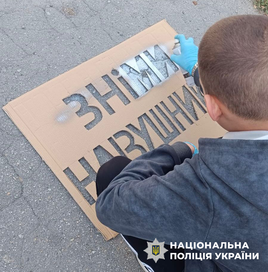 Хлопець замальовує напис "Зніми навушники"