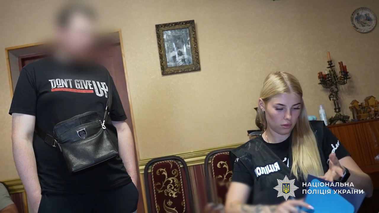 слідча вилучає речові докази, правопорушник стоїть біля неї