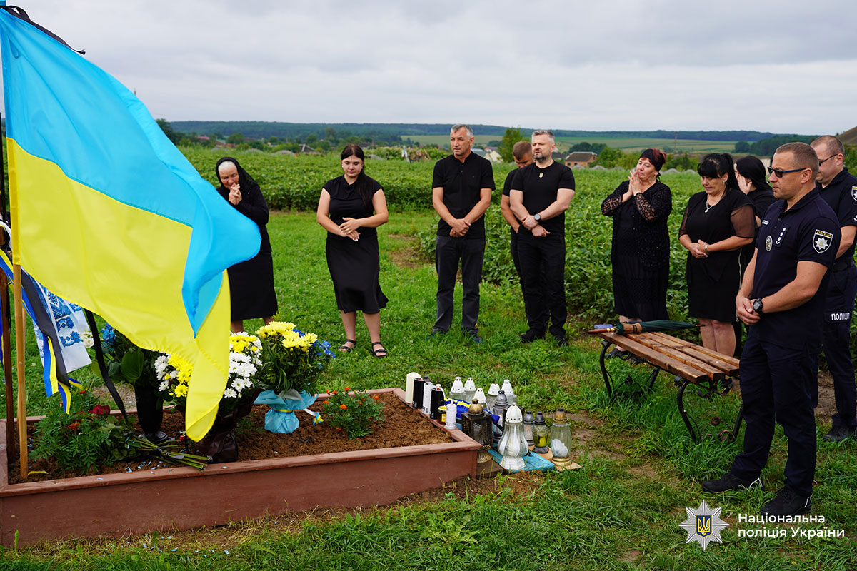 Біля могили поліцейського стоять його колеги, рідні, друзі