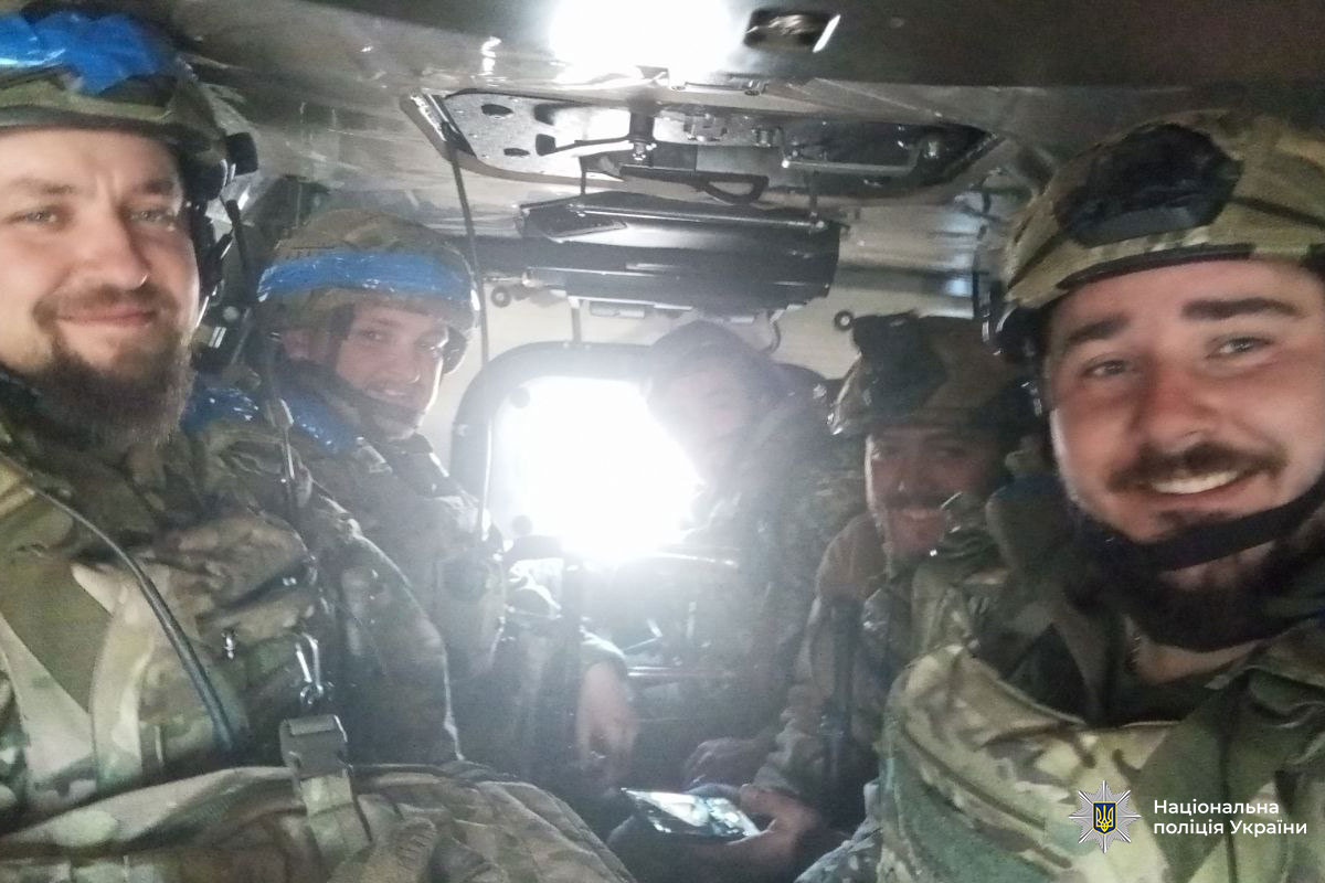Поліцейський разом з побратимами в транспортному засобі в зоні бойових дій