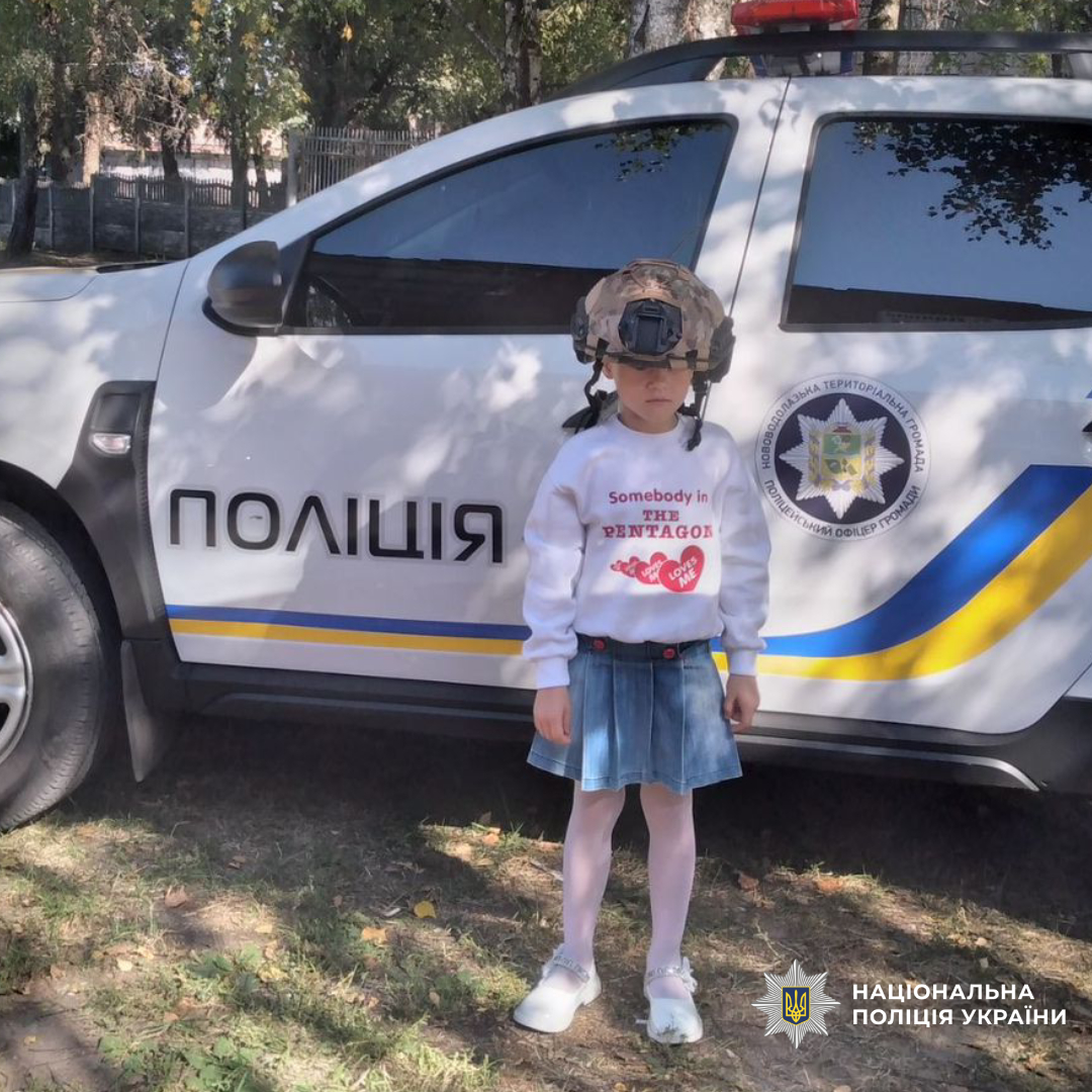 Дівчинка в тактичному шоломі біля поліцейської машини
