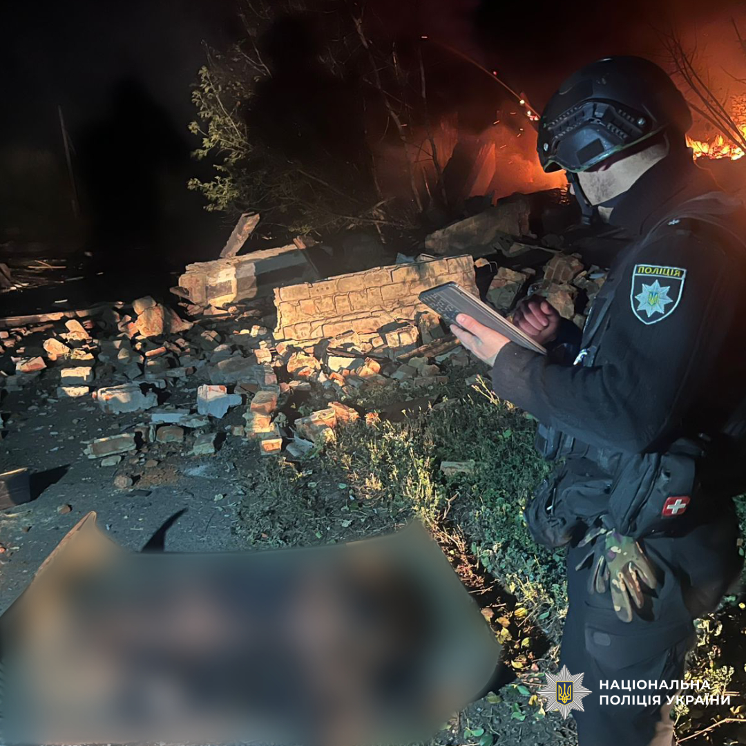 Поліцейський фотографує на планшет загиблу людину в наслідок обстрілу