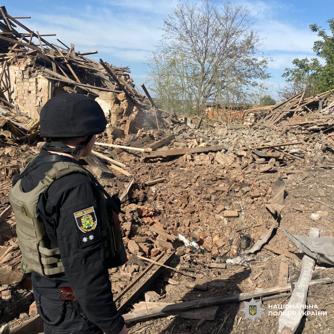 Поліцейський оглядає зруйнований будинок в наслідок обстрілу