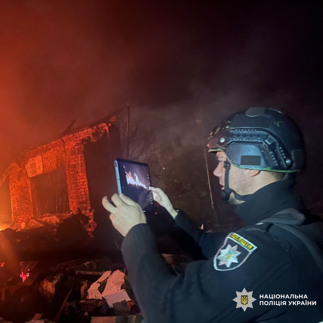 Поліцейський фотографує на планшет руйнування від обстрілу