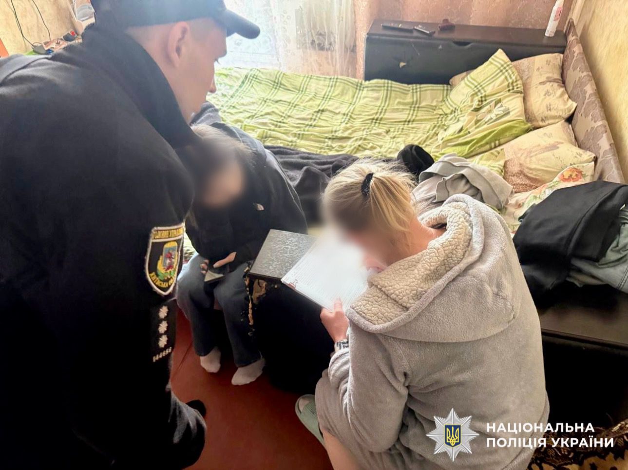 На фото зображено поліцейського, який проводить профілактичну бесіду із дитиною та батьками, а також склав адміністративні матеріали на рідних, стосовно неналежного виконання батьківських обов'язків по вихованню дитини.