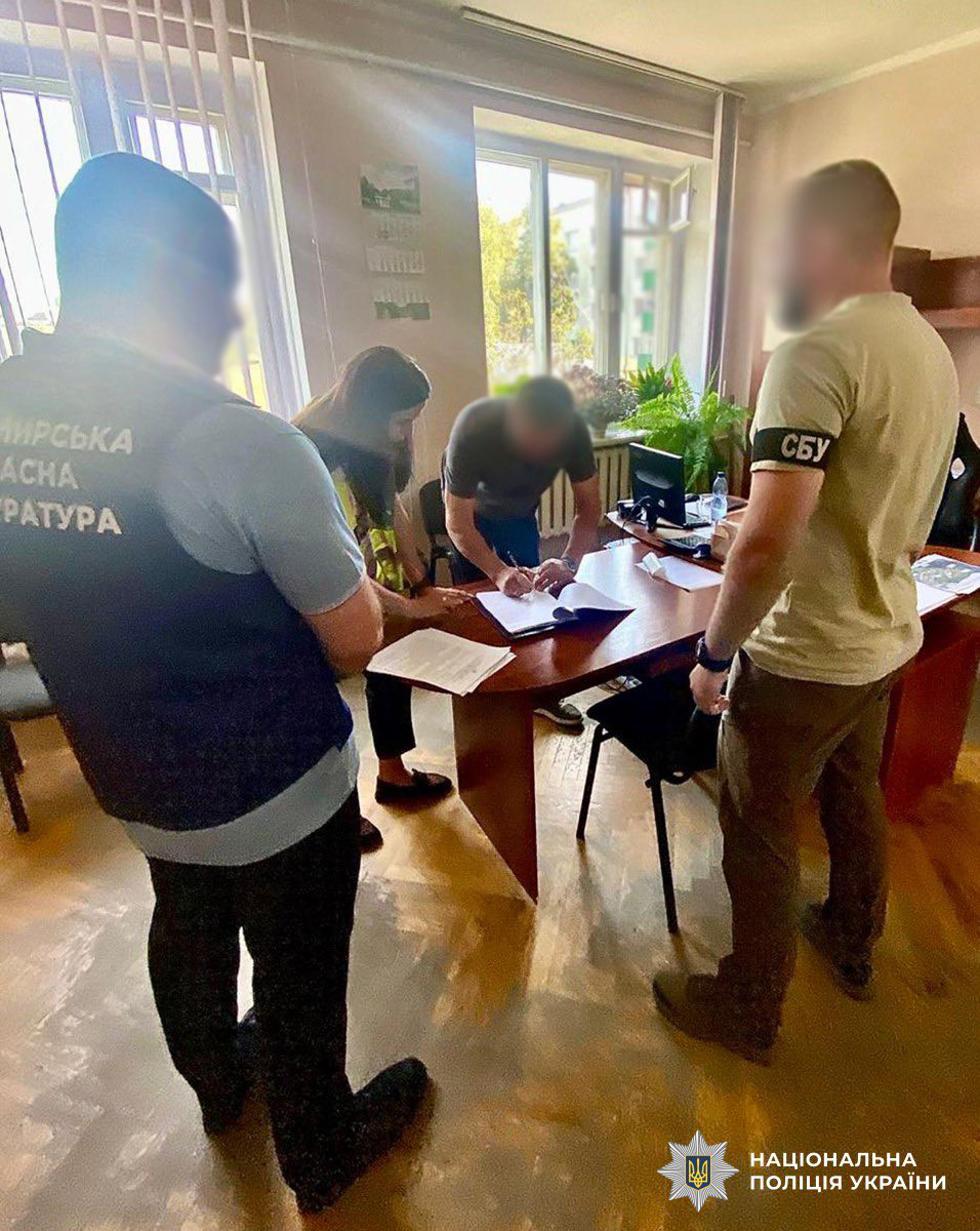 фігурант ставить підпис на документі, біля нього знаходяться співробітник СБУ, прокурор та слідча поліції
