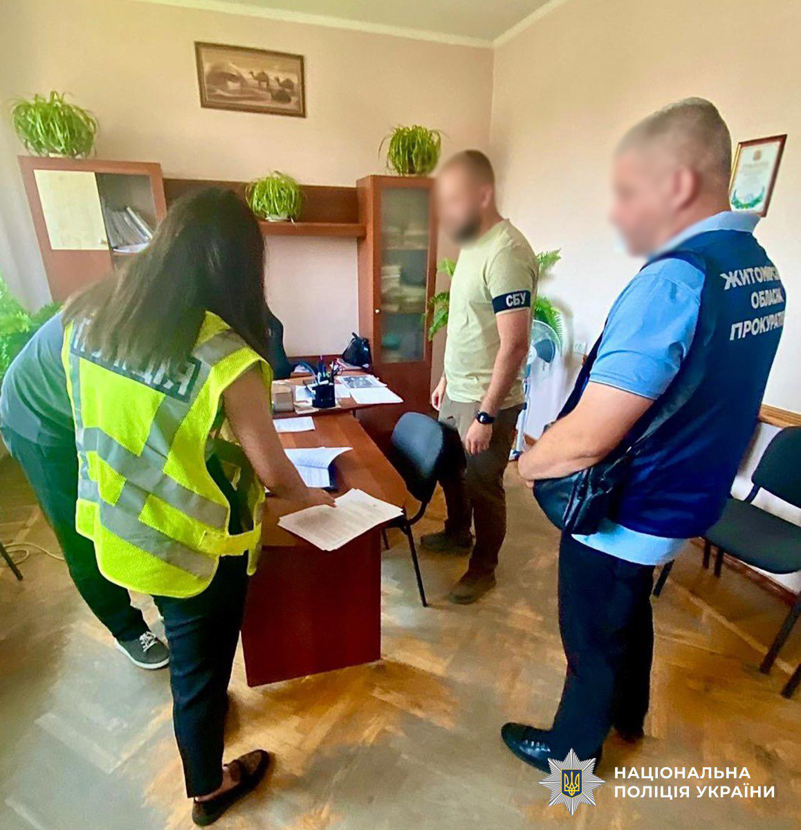 фігурант ставить підпис на документі, біля нього знаходяться співробітник СБУ, прокурор та слідча поліції