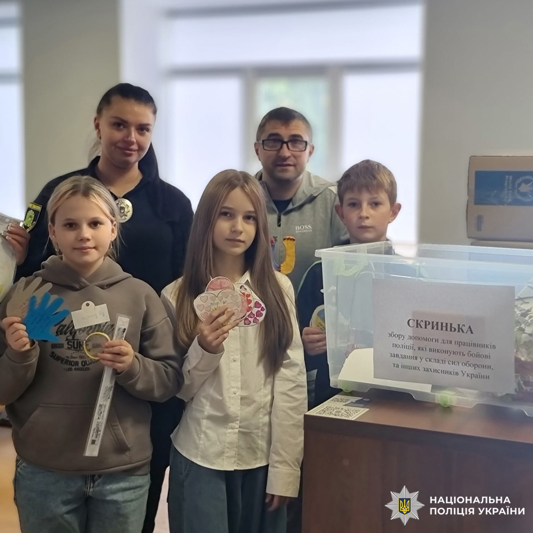 Діти тримають дитячі вироби (серце та долоньку), стоять біля коробки для скриньки побажань.
