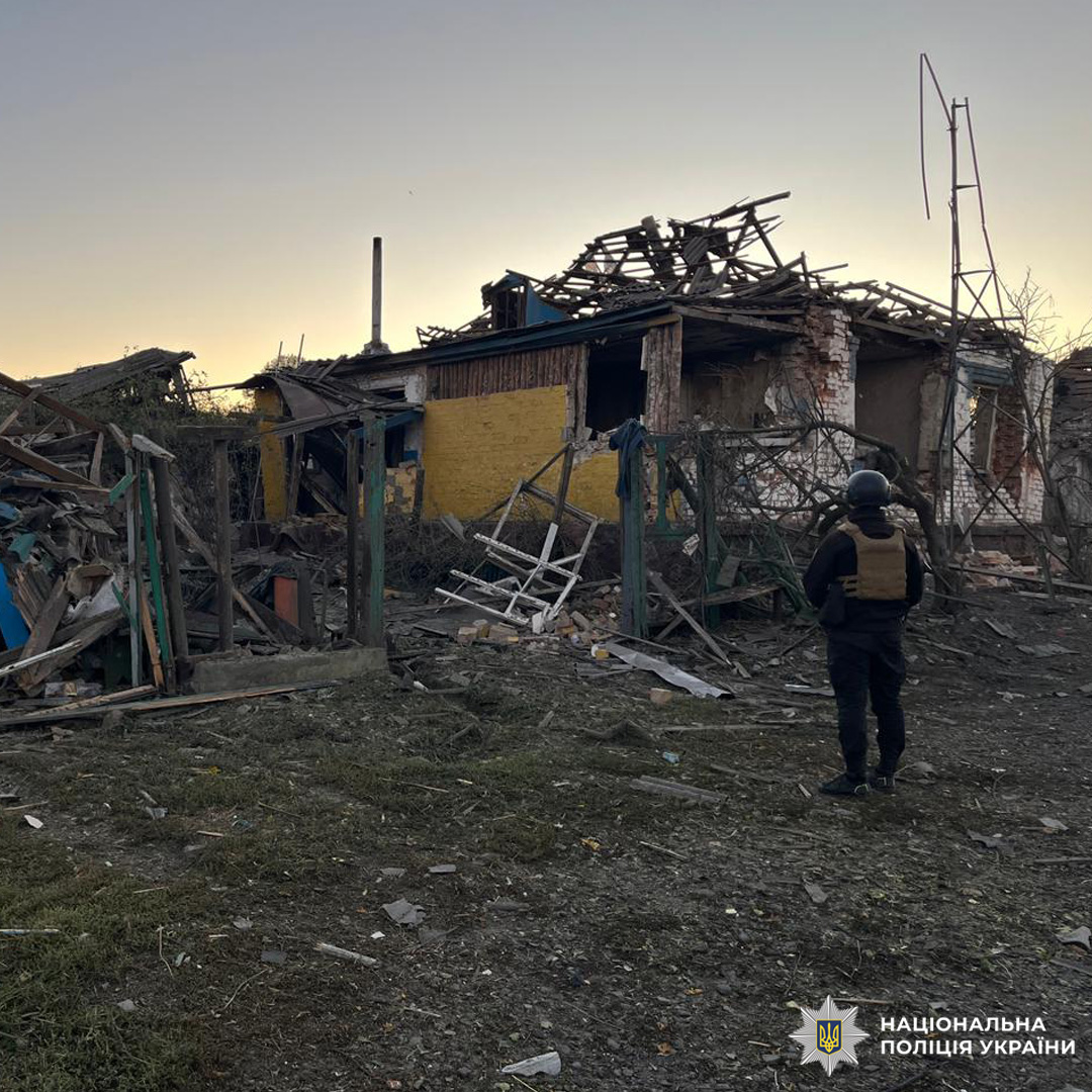 зруйнований будинок рядом стоїть поліцейський.