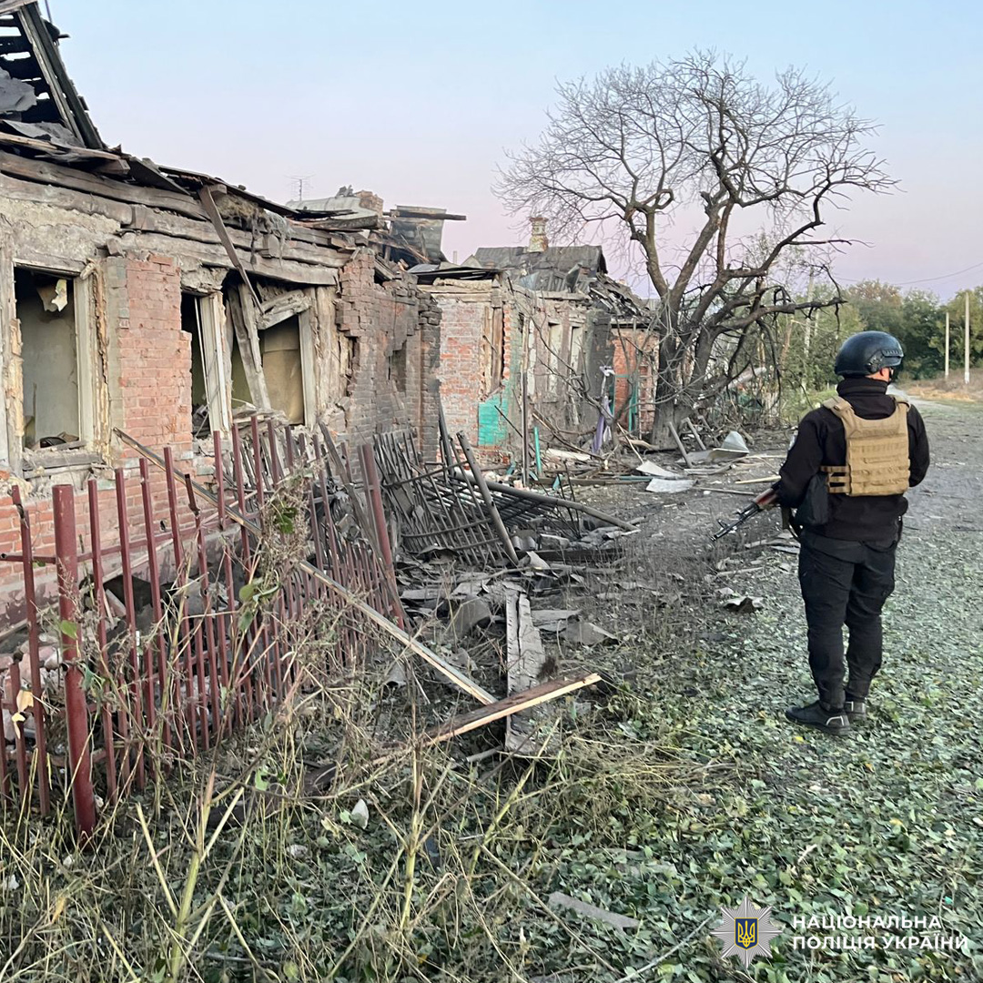 зруйнований будинок рядом стоїть поліцейський.