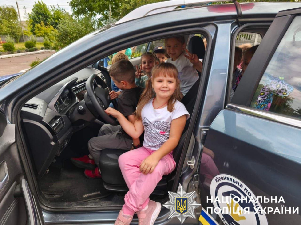 На фото зображені учні, які оглядають службовий транспортний засіб під час заняття із правоохоронцями.