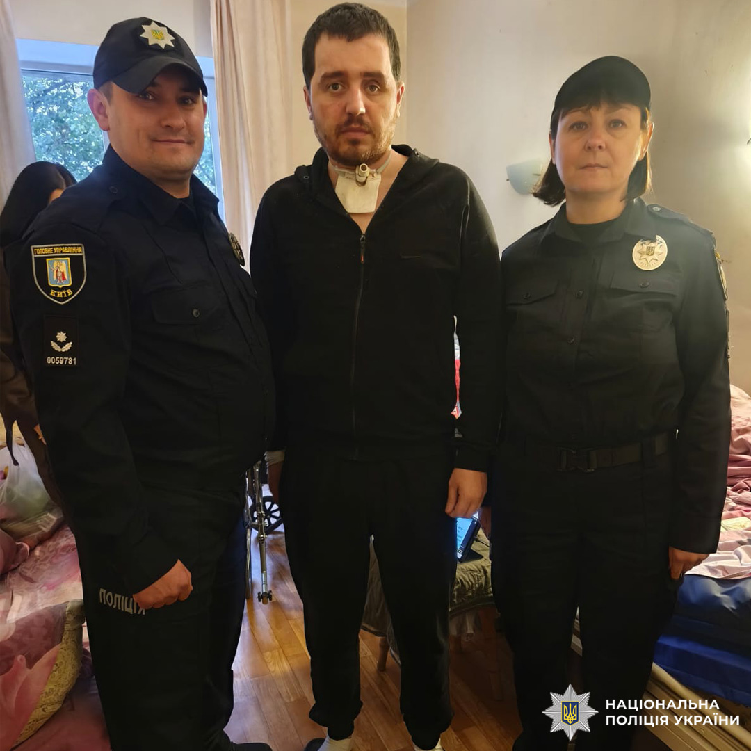 Троє людей у палаті. Двоє у поліцейській формі, один у чорному худі та шльопанцях; на фоні два застелені ліжка, дерев’яна підлога та вікно.