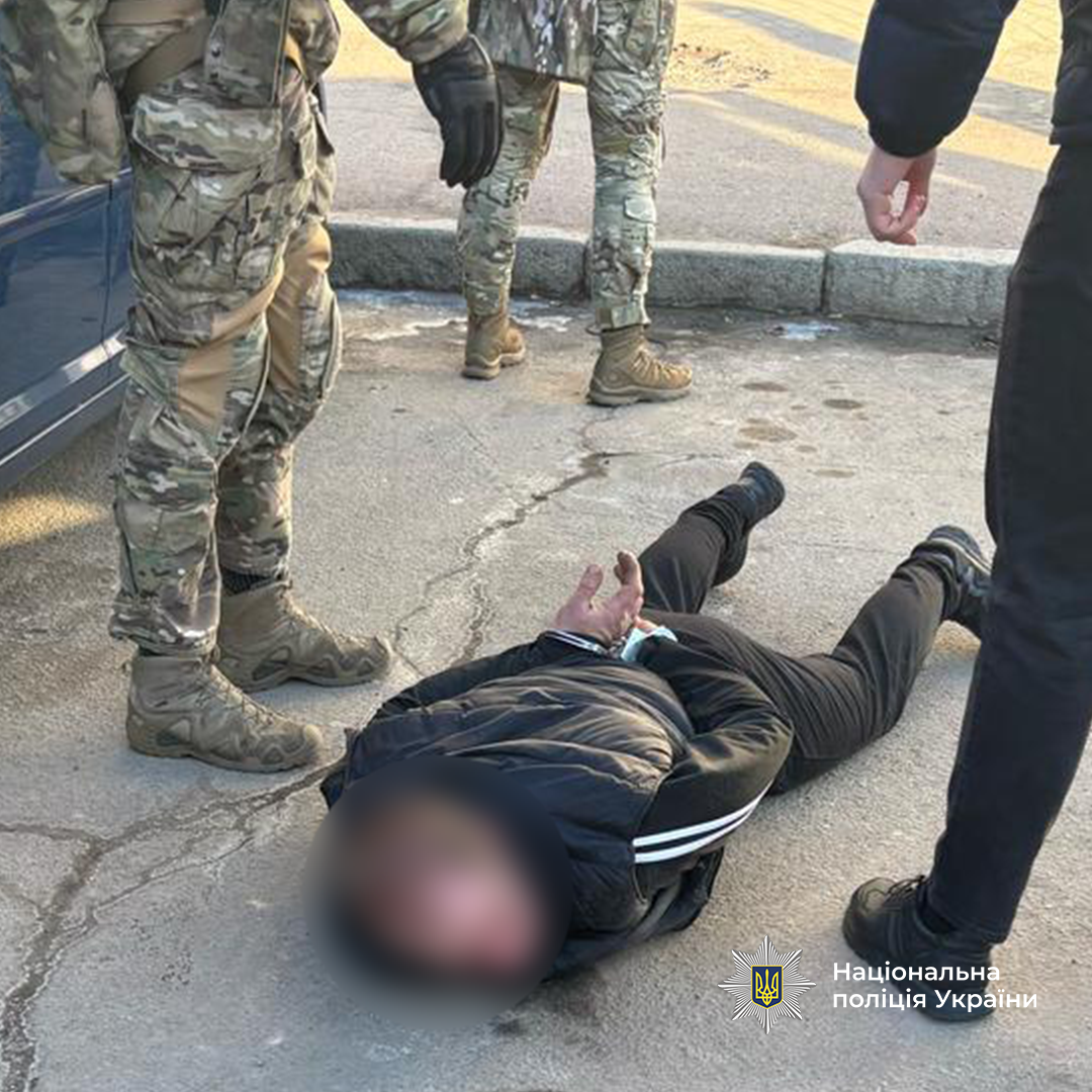 Поліцейські затримали фігуранта. Чоловік лежить на землі у кайданках.