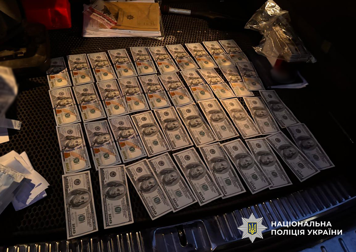 вилучені купюри номіналом по сто доларів лежать в багажнику авто