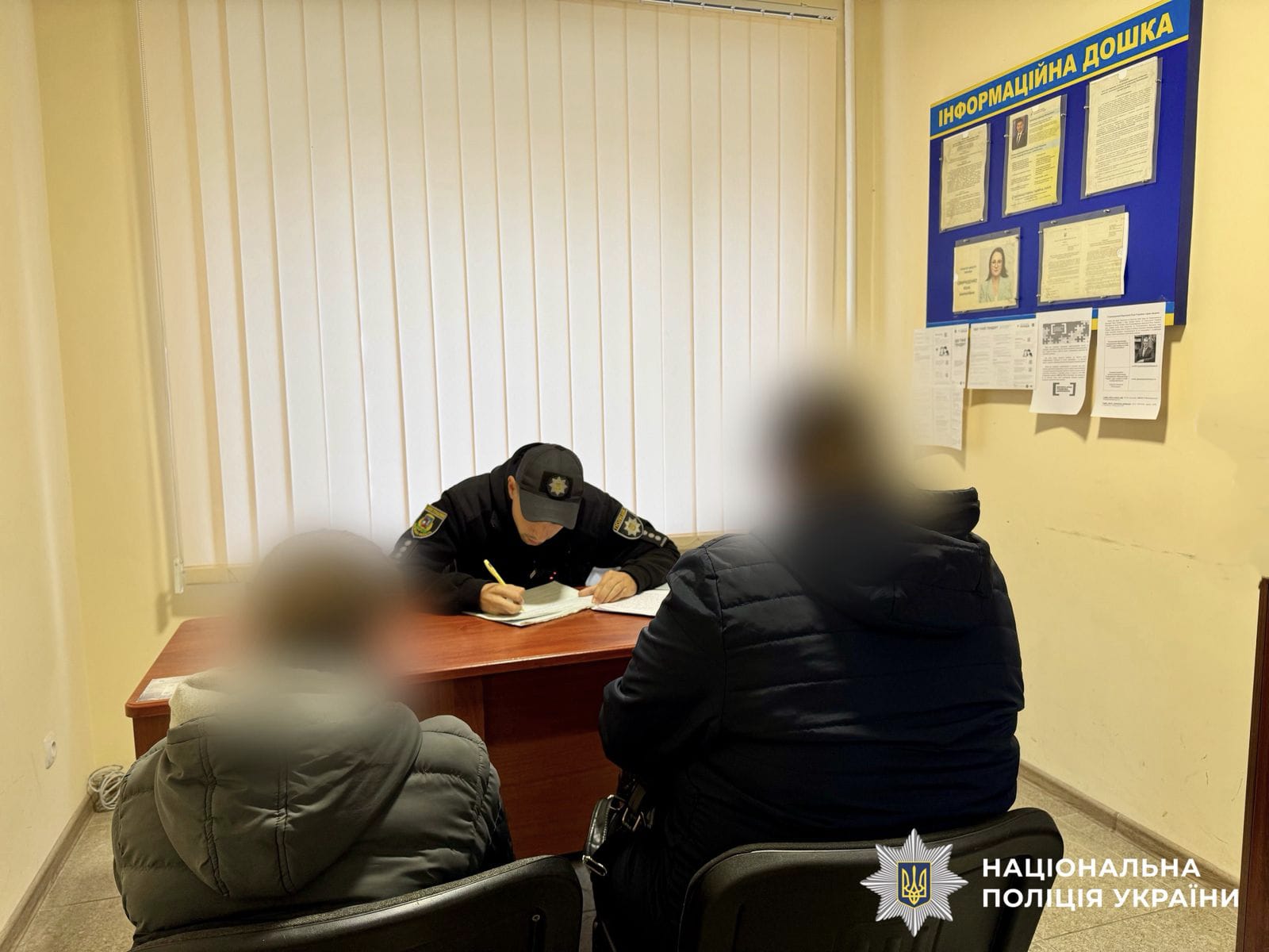 На фото зображений поліцейький, який складає адміністративний матеріал. Навпроти нього н астолом сидять малолітній та його матір.