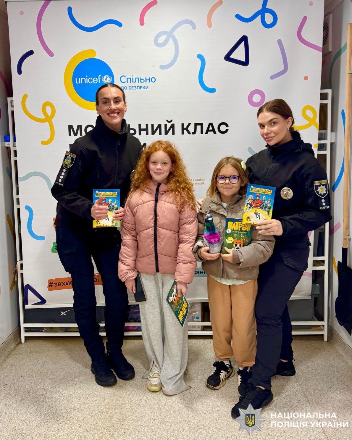 На фото зображені двоє дітей та двоє поліцейських, які стоять обличчям до камери.