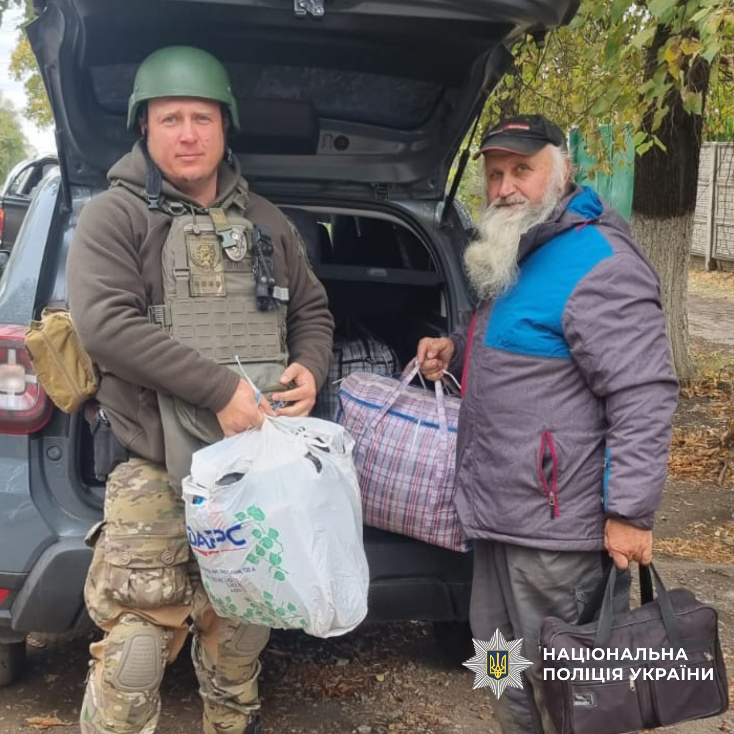 Поліцейський допомагає цивільному з речами під час евакуації