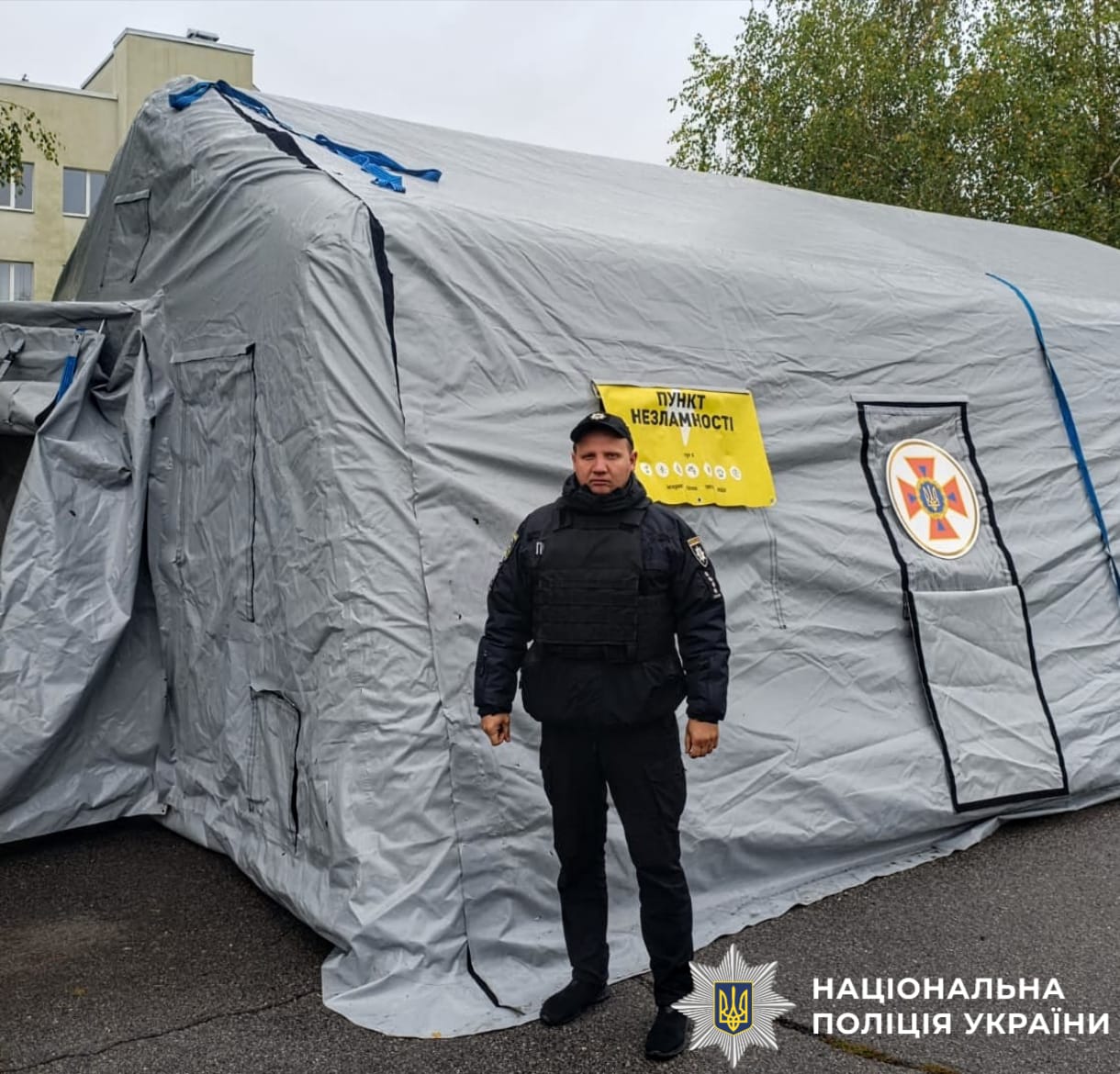 На фото зображено поліцейського, який чергує в пунктні незламності та допомагає містянам під час блекауту.