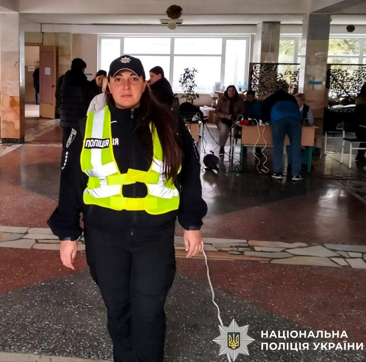 На фото зображено поліцейську, яка чергує в пунктні незламності та допомагає містянам під час блекауту.
