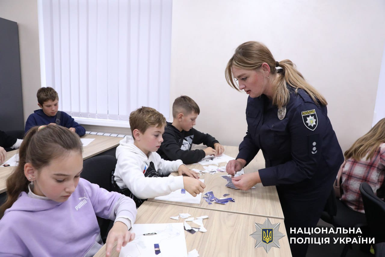 Працівники поліцїі та діти разом роблять поробку.