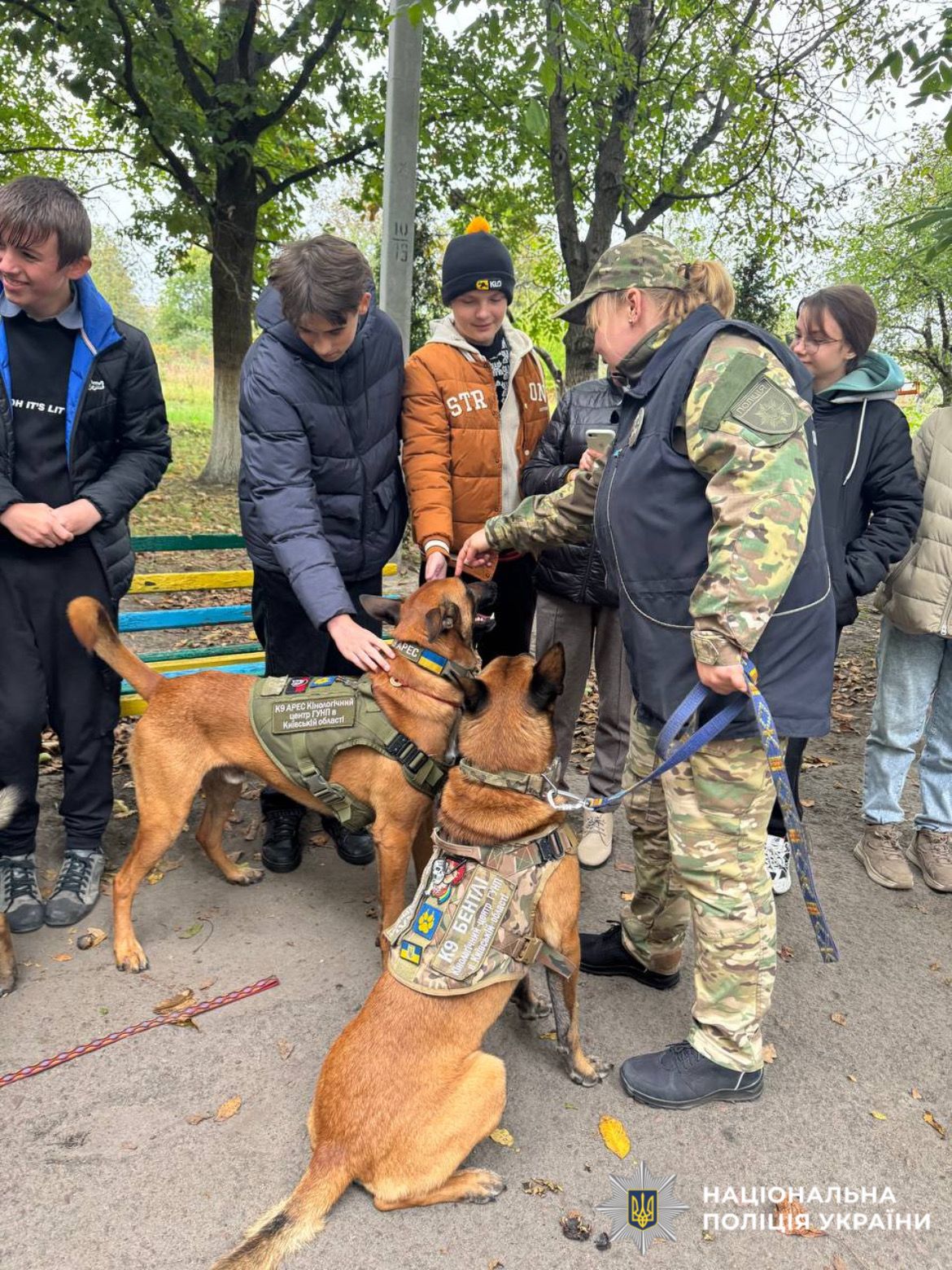 На фото зображено кінологиню поліції Київщини зі службовивими собаками та діти.