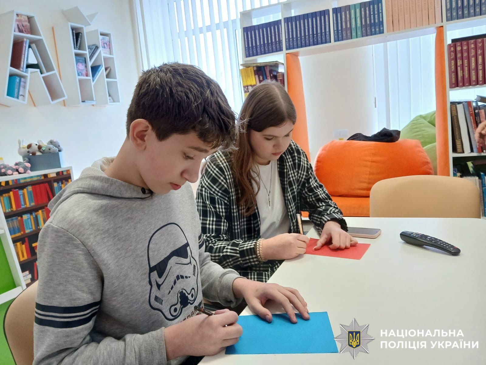 На фото зображені діти, які сидять за партою.