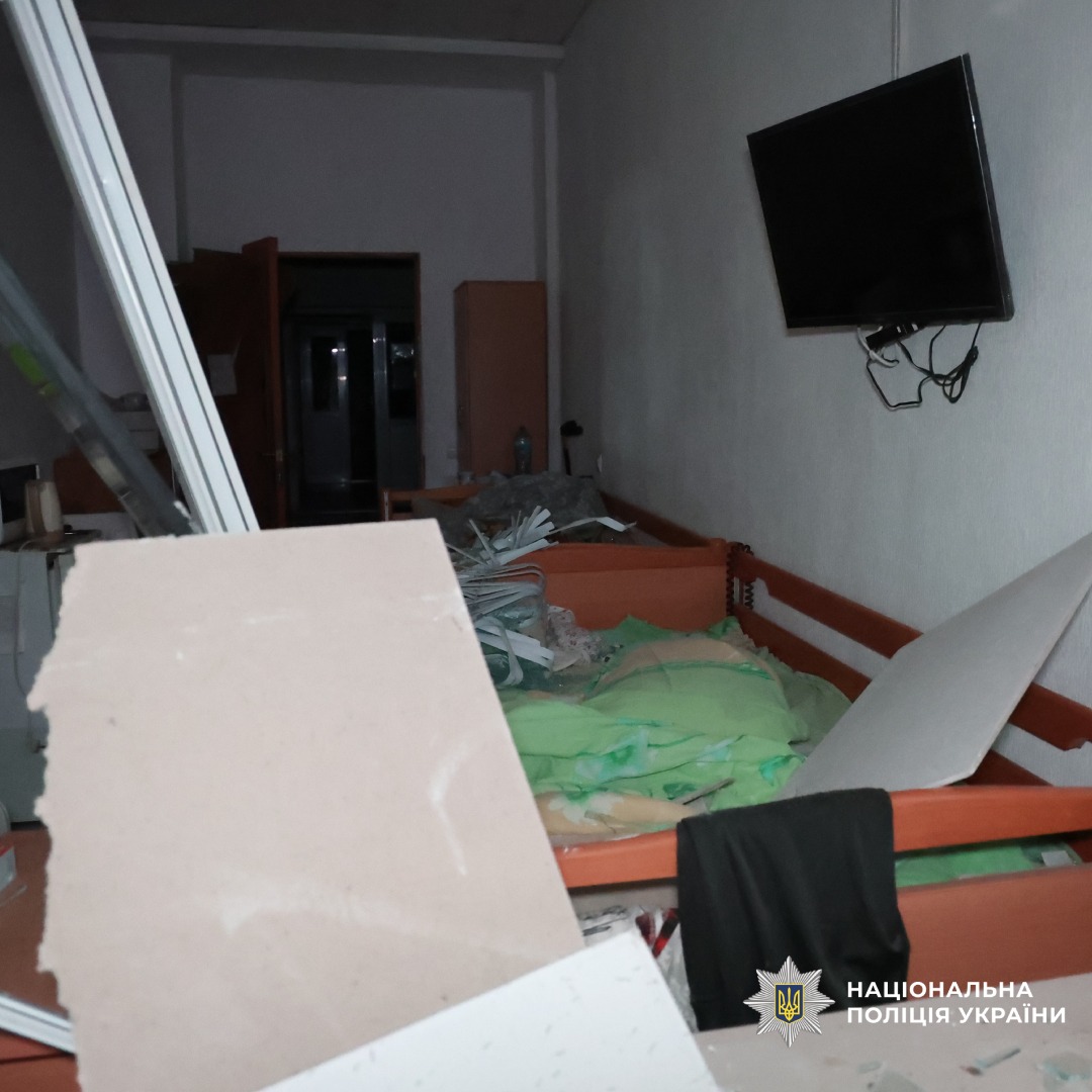 Пошкоджене приміщення після обстрілу у кімнаті видно зруйновані меблі, уламки гіпсокартону та розкидані речі. На стіні висить телевізор.