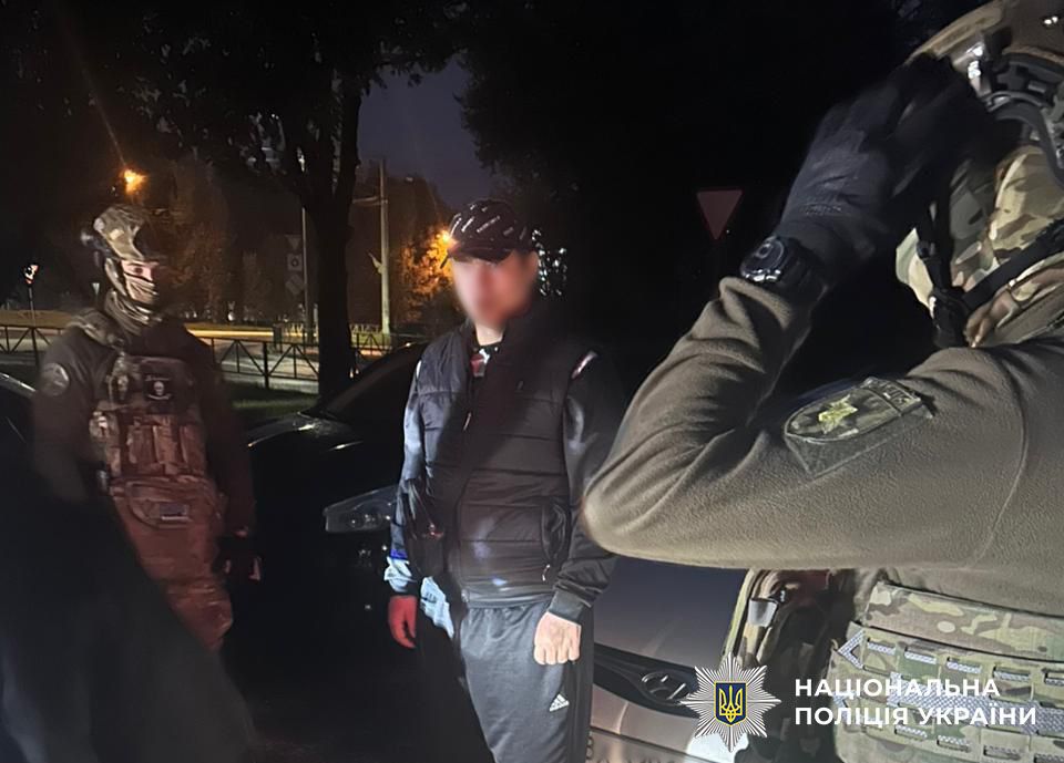 На фото зловмисник та поліцейські біля автомобіля.