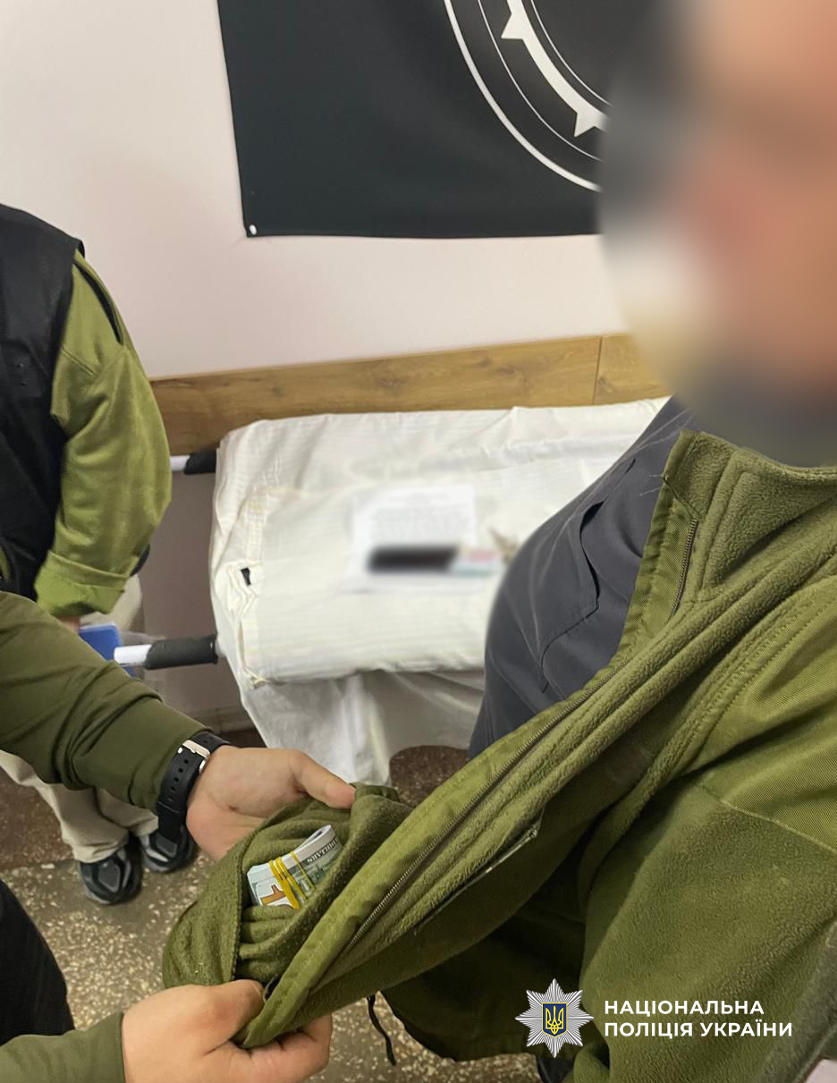 Правоохоронці дістають з кишені фігуранта гроші.