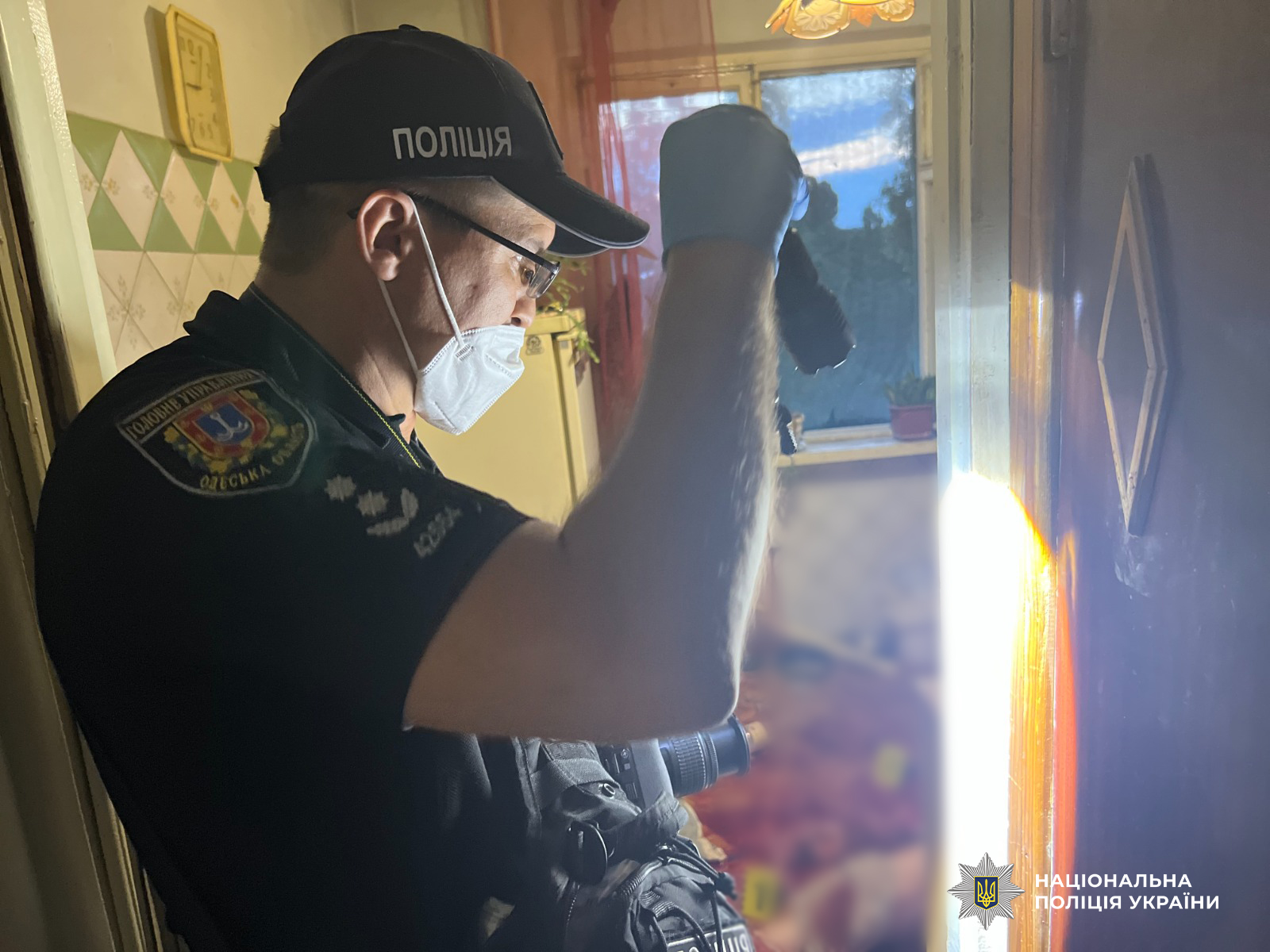 Поліцейський розглядає відбитки на одвірках.