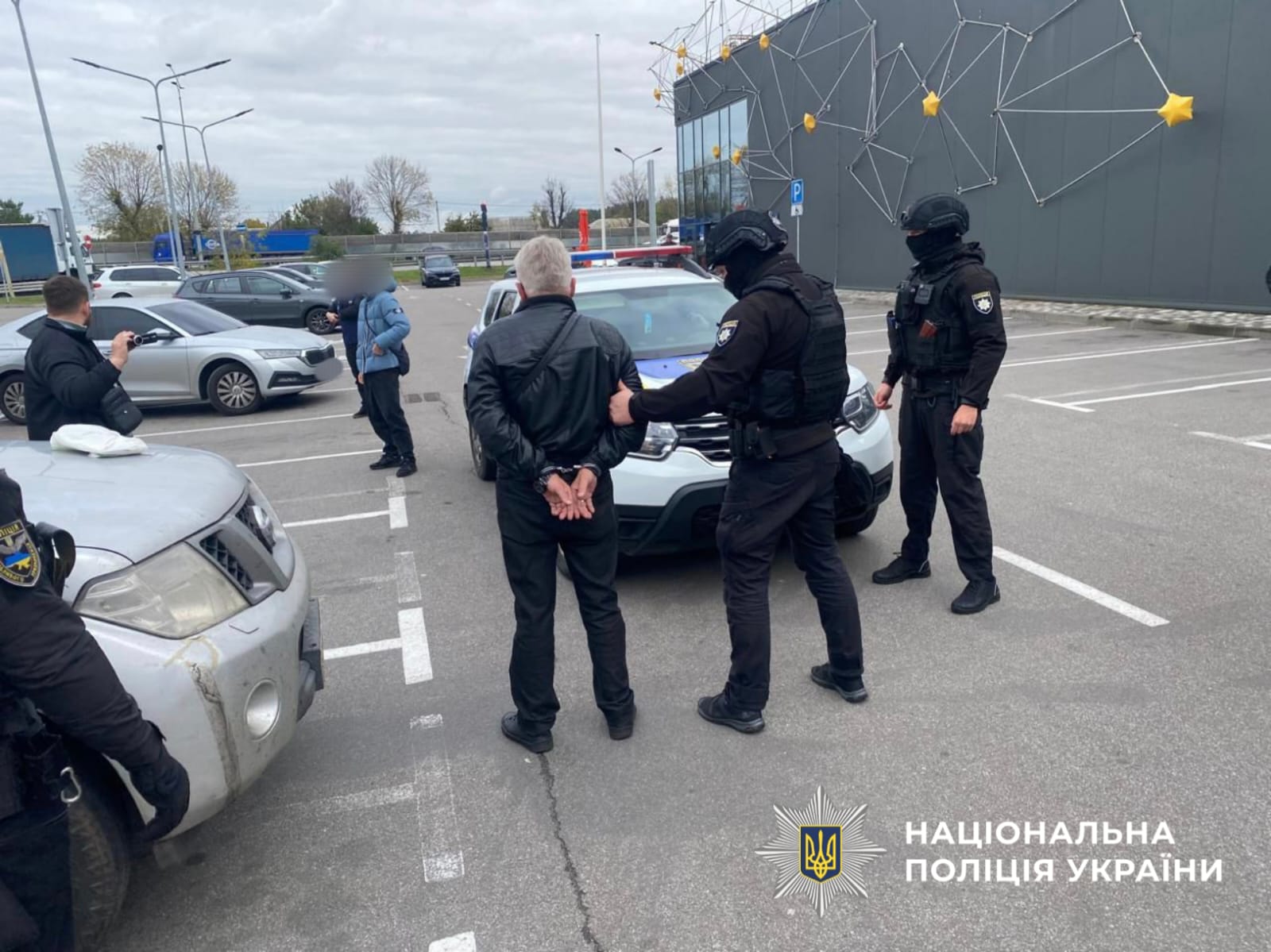 На фото затриманий та спецпризначенці на парковці.