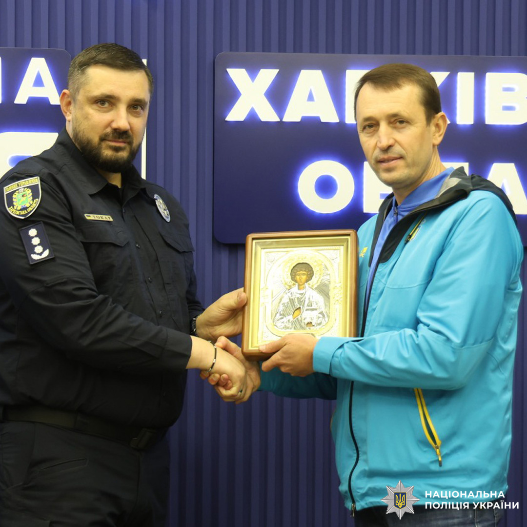 Поліцейський та чоловік у спортивній куртці тримають ікону святого Пантелеймона.