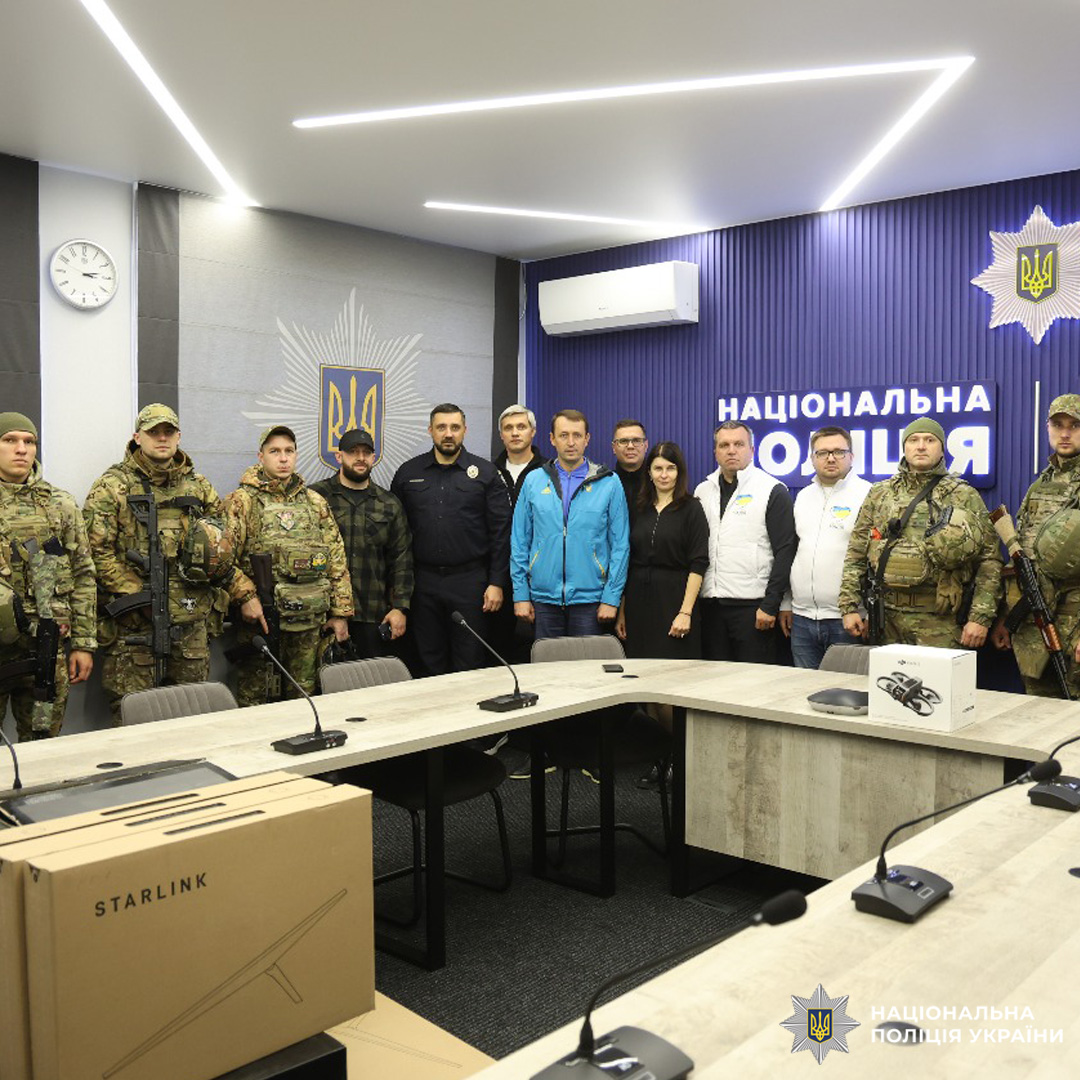 Військові у камуфляжі, поліцейські та цивільні. На передньому плані коробки з обладнанням Starlink, що свідчить про передачу техніки для забезпечення зв’язку.